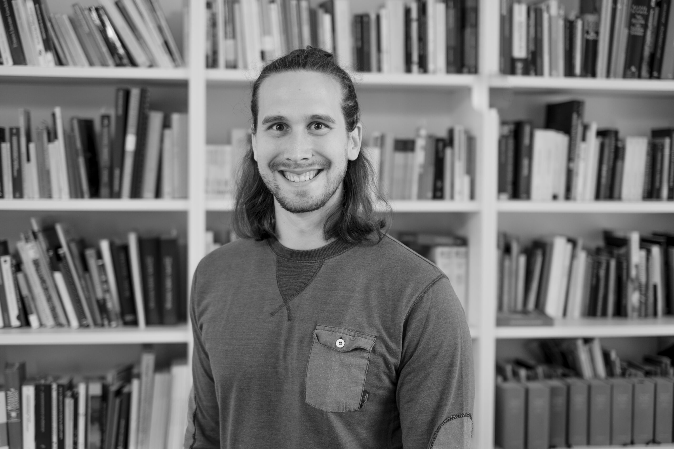 der Wissenschaftler Dr. Elias Bernhart vor Bücherwand